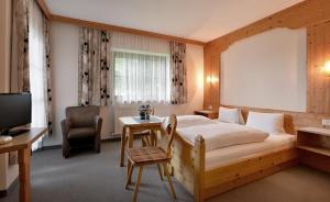 a bedroom with a bed and a desk and a television at Haus Sebastian in Walchsee