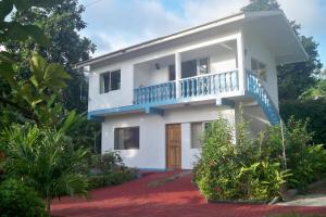 a white house with a blue balcony at Chez Julie in Anse Boileau