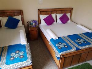two beds in a room with purple and blue pillows at Vijay Residency in Barkot