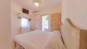 a white bedroom with a bed and a window at i trulli di Holly in Selva di Fasano