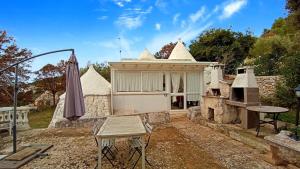 a building with an umbrella and a table and a grill at i trulli di Holly in Selva di Fasano