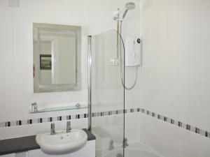 a white bathroom with a shower and a sink at Tarnside in Elterwater