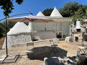 a patio with two chairs and an umbrella in front of a house at i trulli di Holly in Selva di Fasano +18 photos