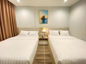 two twin beds in a room with a table at Vũ Gia Phú Quốc Hotel in Phu Quoc