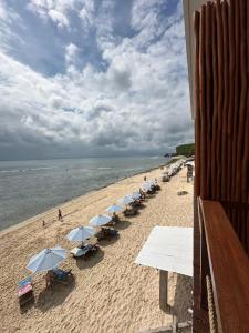 a beach with umbrellas and chairs and the ocean at The Ohm At Thomas Beach in Uluwatu +23 photos