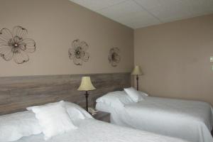 two beds in a hotel room with flowers on the wall at Motel Restaurant Nanook in Cap-Chat