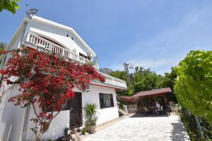 uma casa com flores vermelhas ao lado dela em Apartments Biga em Donji Morinj