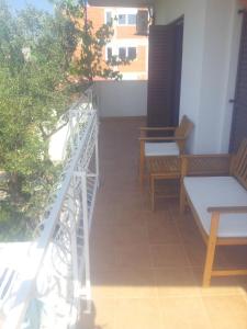 a balcony with two benches and a railing with a view of a building at Apartments Oliva in Rogoznica