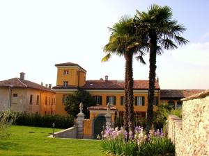 ein großes gelbes Haus mit Palmen und Blumen in der Unterkunft Castello di Brusata - romantic flat with pool in Mendrisio