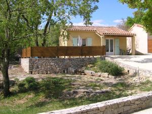 a house with a fence and a stone wall at Gîtes des Campanes in Saint Alban Auriolles