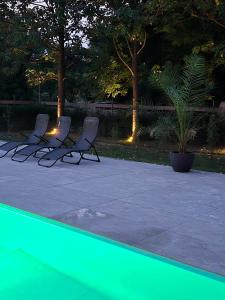 three chairs sitting next to a pool at night at Casa Movilita El DoD in Moviliţa