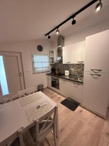 Una cocina con una mesa y un refrigerador blanco. en Apartman Etta - Šišan, en Šišan