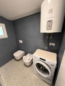 Un baño con lavadora y un inodoro. en Apartman Etta - Šišan, en Šišan 10 fotos más