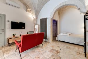 Una sala de estar con una silla roja y una cama. en Gente di Mare Luxury Home, en Fasano