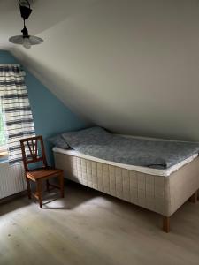 a bed and a chair in a room at Skräddarhuset - Lilla huset in Bonnarp