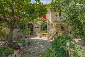 a garden with tables and chairs in front of a building at CHAMBRES D'HÔTES L'Oréliane en Provence SPA in Châteauneuf-de-Gadagne