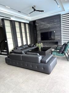 a living room with a black leather couch and a tv at Ivory VIP Villa 3 tầng, bể bơi 5 sao in Lương Sơn +8 photos