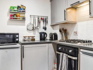 a kitchen with white cabinets and a stove top oven at Coopers Townhouse - Cottage in Worle
