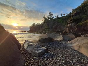 un grupo de rocas en una playa cerca del agua en Studio le Ti coin Charmant, en Saint-Joseph 7 fotos más