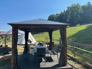 a gazebo with a table and chairs in a field at Tipi-Glamping am Gut Kunterbunt in Kaindorf +7 photos