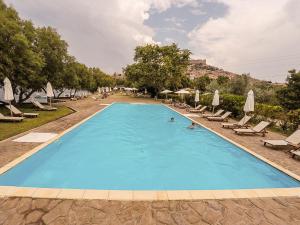 a large swimming pool with lounge chairs and umbrellas at Olive Press Hotel & Apartments in Mythimna