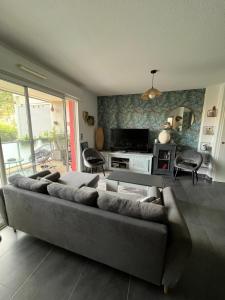 a living room with a couch and a table at Appartement ds résidence avec piscine Mauguio Carnon in Mauguio