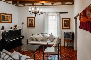 a living room with a couch and a piano at Hotel Ocho Barrios in San Cristóbal de Las Casas