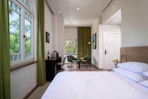 a bedroom with a bed and a desk and window at Schumacher Hotel Haifa in Haifa