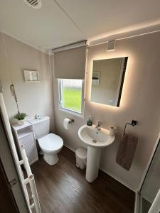 a bathroom with a sink and a toilet and a mirror at Luxury Caravan Escape by the Seaside Port Seton in Prestonpans