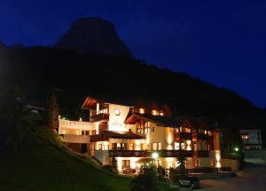 a large building with a clock on it at night at Alpin Apartments Colfosco in Colfosco