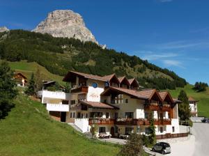 een gebouw op een heuvel met een berg op de achtergrond bij Alpin Apartments Colfosco in Colfosco
