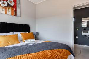 a bedroom with a bed with orange pillows and a sink at Lowveld Getaway in Nelspruit