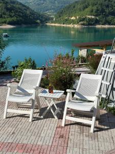 two white chairs and a table with a view of a lake at Vikendica Plavi Mir in Konjic +7 photos