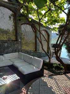a white couch sitting on a patio under a tree at Vikendica Plavi Mir in Konjic