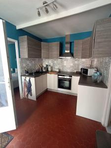 una cucina con armadi bianchi e pavimento rosso di Maison de plage avec grande terrasse privée a Leucate Plage Altre 14 foto