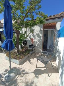 un ombrellone blu e sedie su un patio di Maison de plage avec grande terrasse privée a Leucate Plage