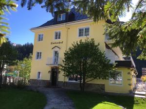 a yellow building with a tree in front of it at Hotel Lindenhof in Bad Gastein
