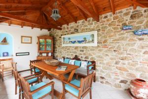 a dining room with a table and chairs and a stone wall at Studios Villa Eleni in Skiathos