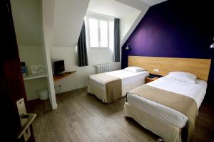 a hotel room with two beds and a purple wall at Hôtel De France - Restaurant L'insolite in Douarnenez +59 photos