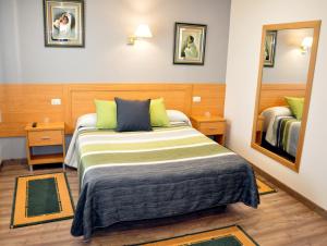 um quarto de hotel com uma cama e um espelho em Hostal Paz em Gondomar