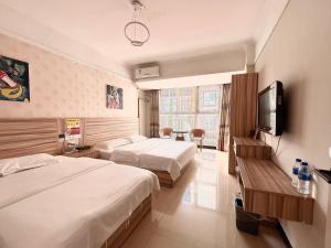 a hotel room with two beds and a flat screen tv at MAXHILL inn悦季时光酒店 in Jinghong