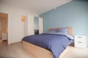a bedroom with a large bed with blue sheets at Duinenblik 3 in Nieuwpoort