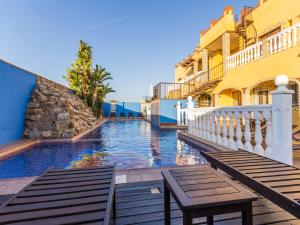 ein Pool mit zwei Bänken neben einem Gebäude in der Unterkunft Oasis de Cádiz in Conil de la Frontera
