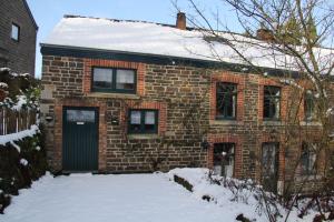 une maison en briques avec une porte verte dans la neige dans l'établissement Gîte les beaux-arts, à Ronzon