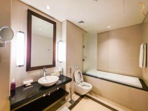 a bathroom with a sink and a toilet and a mirror at Azure Crest 2BR - Ocean View Apartment Near Marina Mall in Abu Dhabi