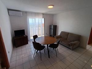 a living room with a table and chairs and a couch at Apartmani Noel in Lun