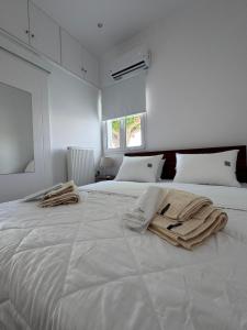 a white bedroom with two beds with towels on it at Agia Anna Horizon in Kranidi