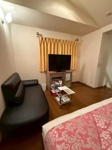 a room with a couch and a tv and a bed at HOTEL i in Takahata