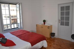 a bedroom with a bed with a red blanket and a window at Hostel Rossio Alcobaça in Alcobaça