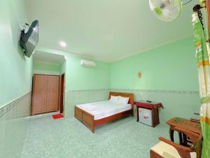 een kleine slaapkamer met een bed en een tafel bij Anh Linh Guest House in Mũi Né